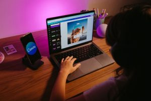 Canva pro Teen working on graphic design using laptop at home with creative tools.
